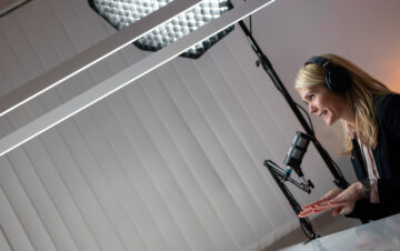 Side view of two Caucasian women recording a radio talk show in a studio.