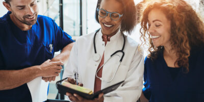 Smiling group of diverse doctors discussing a patient's dignosis while standing together in a hospital corridor