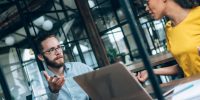 man woman talking at desk