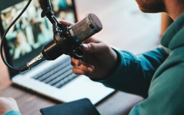A man host streaming his audio podcast using microphone and laptop at his small broadcast studio, close-up A man host streaming his audio podcast using microphone and laptop at his small broadcast studio, close-up