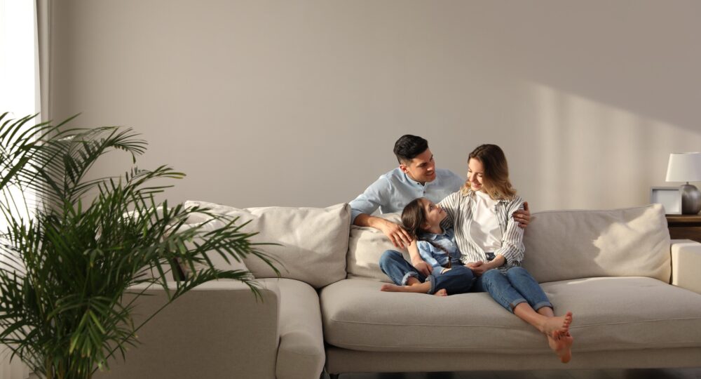 Family with little daughter resting on sofa in living room